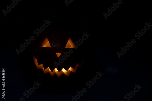 Halloween pumpkin in the dark with lighted candle inside. horror theme and Hallowe'en.
