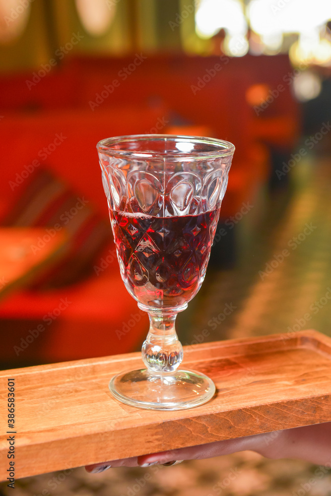 Holding wine glass inside on a wooden board. Eating out in restaurant concept.