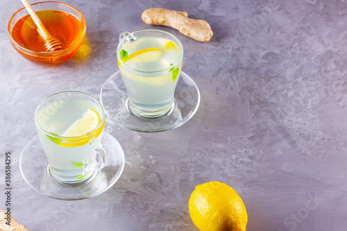 Ginger tea with lemon on a gray background. Two cups of ginger tea and ingredients for its preparation. Copy space. Top view