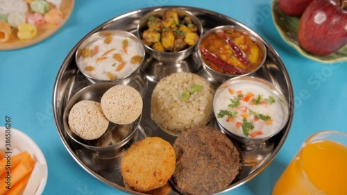 A slow focus of the camera to a traditionally prepared fasting food platter. Food items eaten after a day-long fast during the Navratri festival - juice  fruits  Papad  Cholai Laddu  Kuttu Puri  Kh... photo