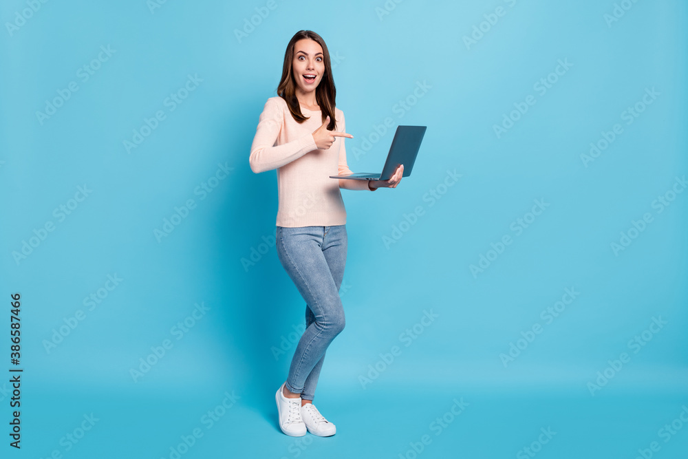 Full length body size view of her she nice attractive cheerful cheery glad amazed girl holding in hands demonstrating using laptop isolated over bright vivid shine vibrant blue color background Full length body size view of her she nice attractive cheerful cheery glad amazed girl holding in hands demonstrating using laptop isolated over bright vivid shine vibrant blue color background