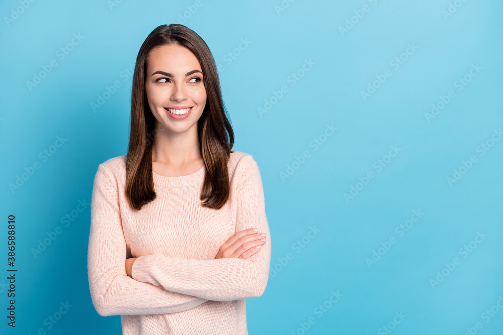 Photo of positive attractive lady look empty space cross hands wear beige sweater isolated over blue color background Photo of positive attractive lady look empty space cross hands wear beige sweater isolated over blue color background
