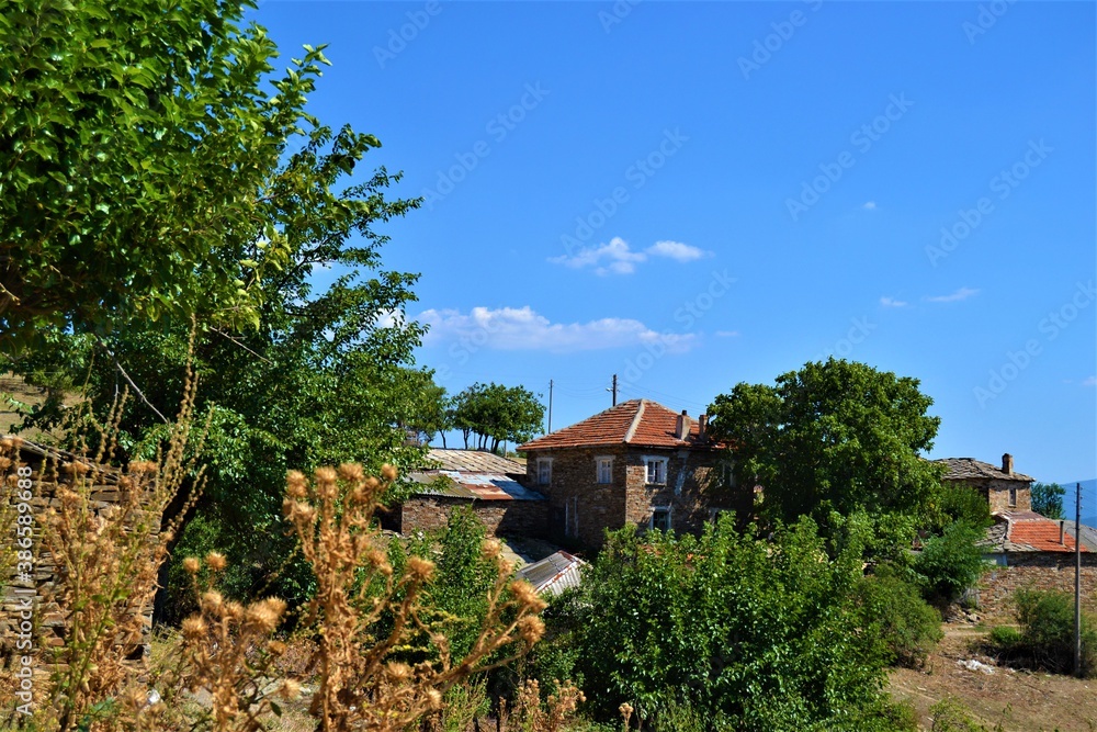 Bulgaria and views from cute and small villages during bright day. Old style village house made of stone and mut. Vintage  buildings in cute village during sunny day and blue sky.