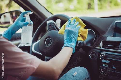 Cropped photo of driving teacher girl sit car wash rag disinfect antiseptic bottle steering wheel before student come ride learn wear blue latex gloves in city center photo