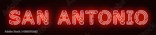 Glowing neon sign with the inscription of the USA city of San Antonio. In red and orange colors. Against a brick wall. All elements are isolated.