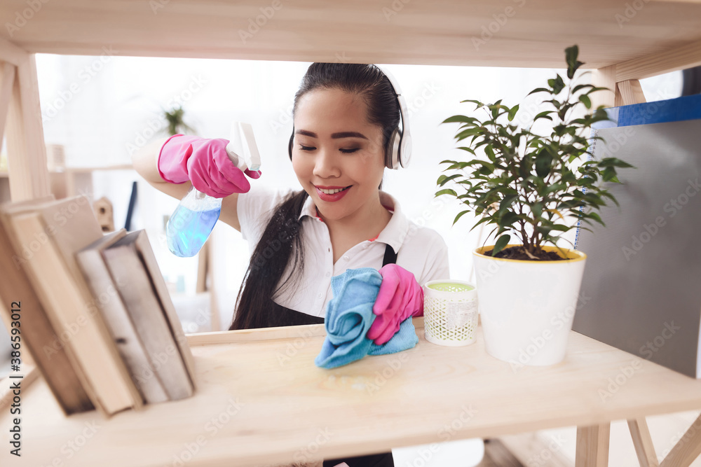 Asian woman with spray and rag rubs shelves. Asian woman with spray and rag rubs shelves.