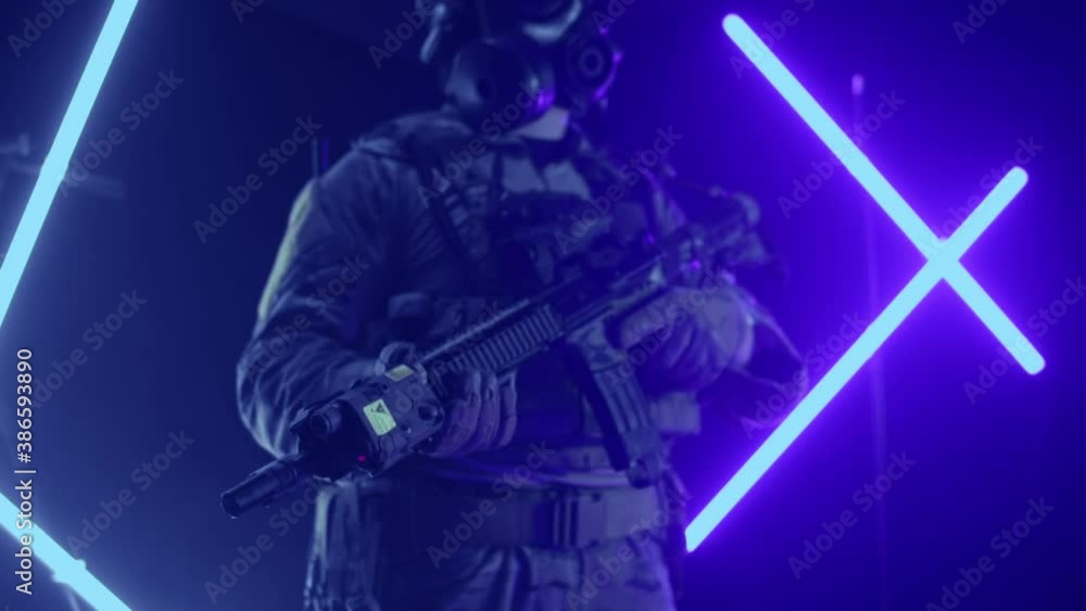 A soldier in uniform with a rifle in his hands on a multi-colored background in the studio. Game concept with weapons and laser tag and paintball, slow mo A soldier in uniform with a rifle in his hands on a multi-colored background in the studio. Game concept with weapons and laser tag and paintball, slow mo
