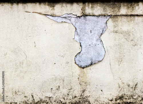 Peeling cream paint on a white concrete wall