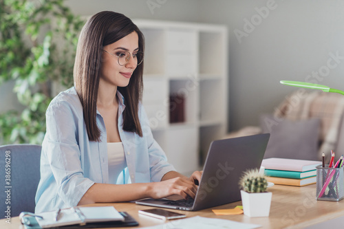 Photo of lovely young girl sit desktop use computer look screen wear eyewear shirt in home office indoors