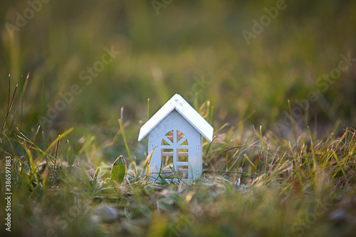 Figures of small white wooden houses on the grass close-up. The cottage is in a rural location and village, building, project, moving , mortgage, rent and purchase real estate. Copy space