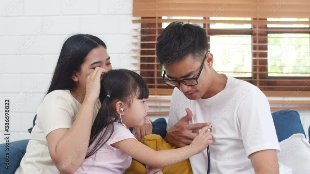 Happy cheerful Asian family dad, mom and daughter playing funny game as doctor having fun on sofa at home. Self-isolation, stay at home, social distancing, quarantine for coronavirus prevention. Happy cheerful Asian family dad, mom and daughter playing funny game as doctor having fun on sofa at home. Self-isolation, stay at home, social distancing, quarantine for coronavirus prevention.