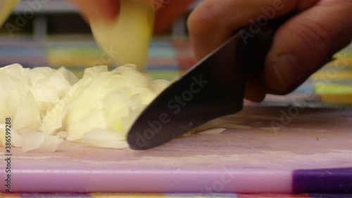Close up hands cutting, slicing and dicing onions with a sharp knife.