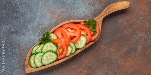 Cucumbers and tomatoes cut on a wooden board.
