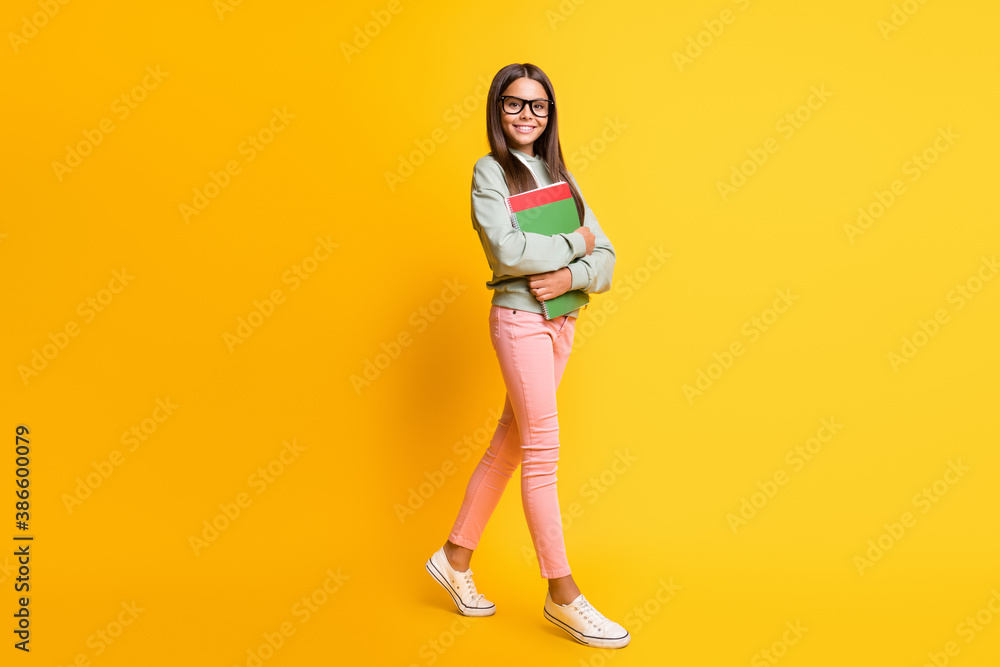 Full length photo of beautiful pupil go studying wear hoodie isolated on yellow color background Full length photo of beautiful pupil go studying wear hoodie isolated on yellow color background