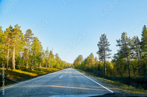 View from car windscreen with stripe relief to highway, tundra and blue sky in norht region at a sunny day photo