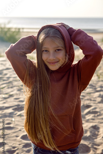 portrait of a girl with long hair standing on a sandy beach