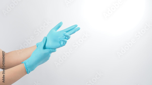 Right hand is pulling blue latex gloves on white background.