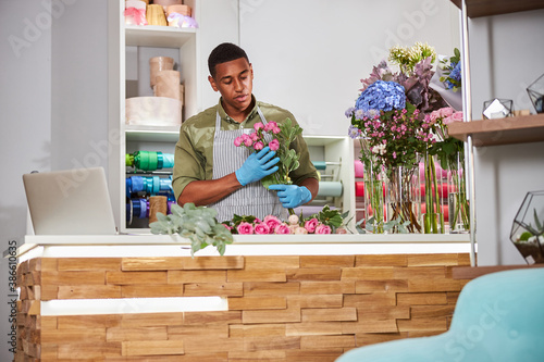 Young florist working in shop with laptop