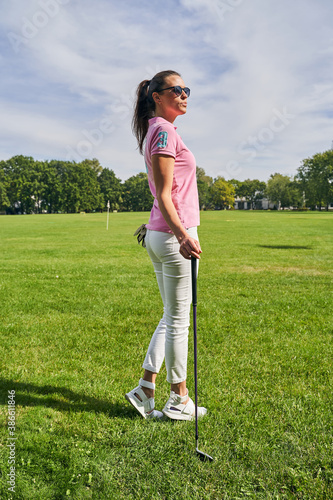 Female golfer with a club staring into the distance