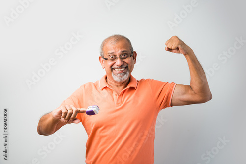 Old Indian asian man with electronic thermometer and oximeter gadget photo