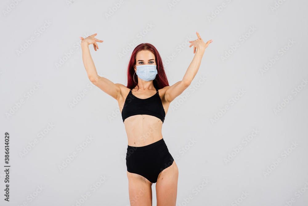 Female dancer in the styles of strip-plastic and pole dance with face mask on light background.