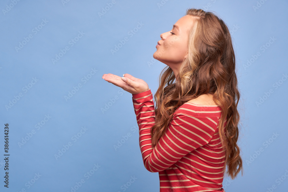 Fototapeta premium Close up profile side view portrait of her she is cute attractive cute content cheerful cheerful girl blows a kiss on the background of the shade color