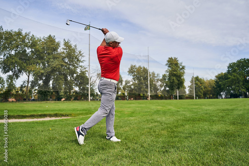 Fit man swinging his wedge golf club outdoors