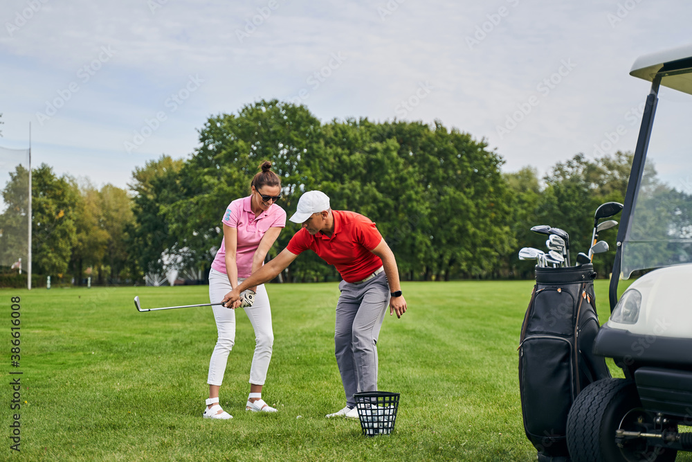 Obraz premium Smiling lady golfer mastering the golf basics