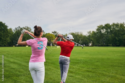Two athletes practicing golf swings on the driving range