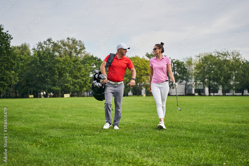 Female golfer looking at her pleased trainer