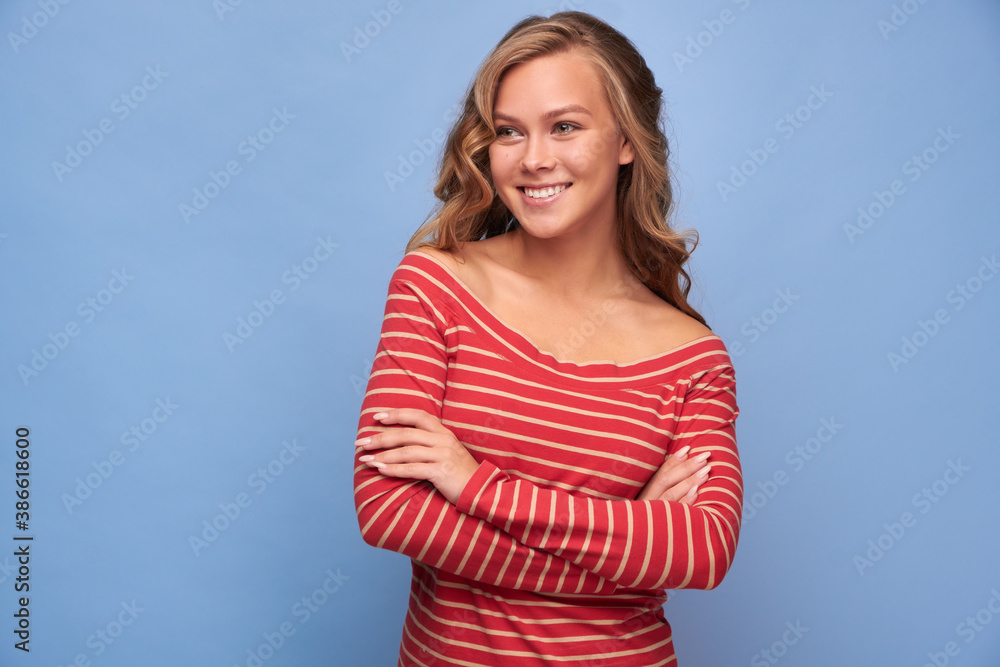 Portrait of a smiling girl with her hands folded at the waist in red clothes with yellow stripes on a blue background Portrait of a smiling girl with her hands folded at the waist in red clothes with yellow stripes on a blue background