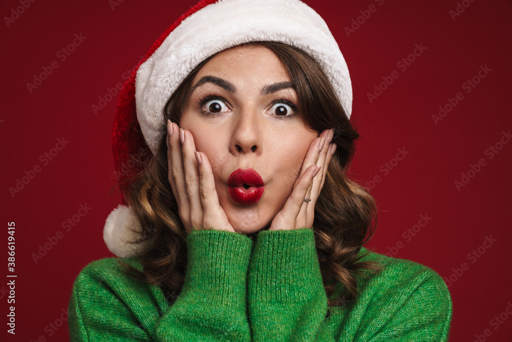Beautiful girl in Santa Claus hat expressing surprise on camera Beautiful girl in Santa Claus hat expressing surprise on camera