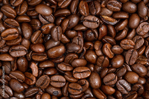 Roasted dark coffee beans background from close up. Full frame shot of brown aroma seeds for banner. A lots of black pure crops in detail with texture.