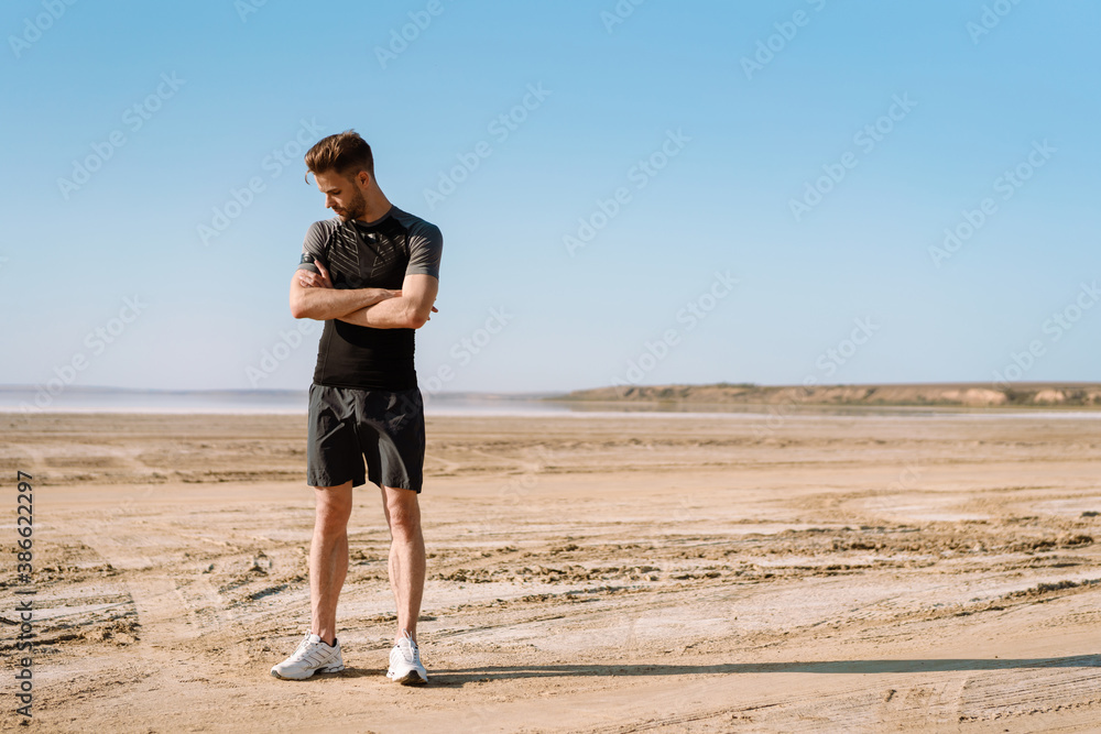 Confident young sportsman standing at beach