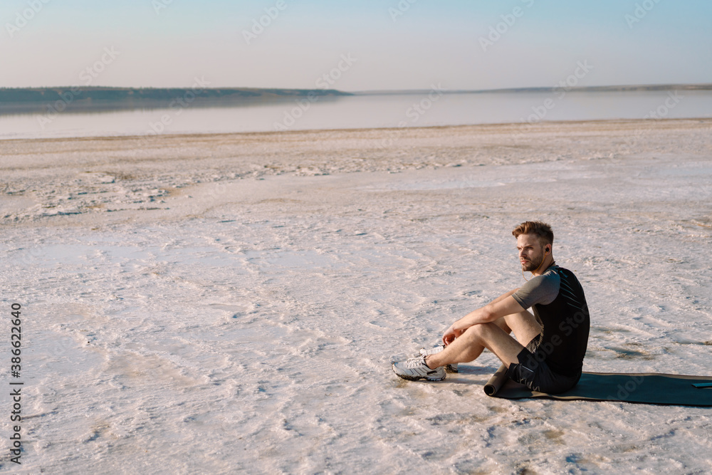 Attractive young sportsman sitting at the salt lake