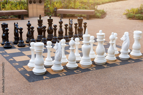 Outdoor chess board with big plastic pieces. Giant size chess in public area zone. Close up big pieces and giant chess board of street chess in the park