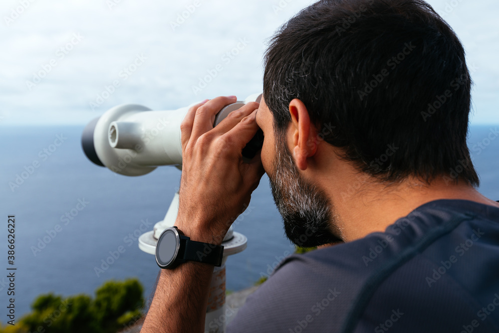 Young traveler man looking through binoculars