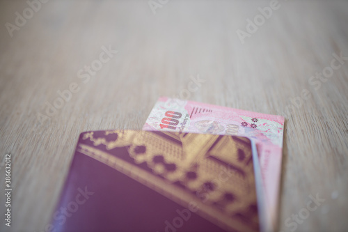 One Hundred Thai Baht Bill Partially Inside a Sweden Passport