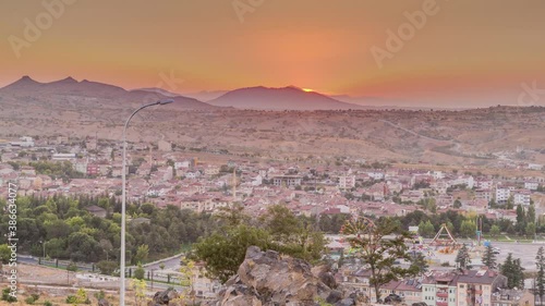 Sunset view from old castlethe in historical city town of Nevsehir aerial timelapse. Panoramic skyline with hills and park at evening photo