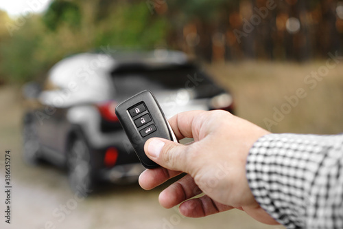 Man hand holds car key against blurred car. New car concept.