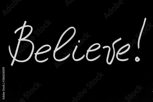 Handwritten inscription Believe in white marker on a black background