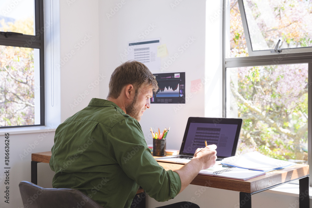 Man working while sitting on his desk at home Man working while sitting on his desk at home