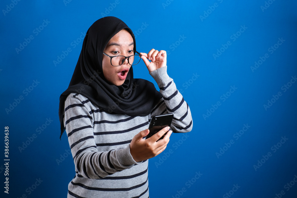 Young Muslim Woman Shocked Expression, Looking at Her Phone Young Muslim Woman Shocked Expression, Looking at Her Phone