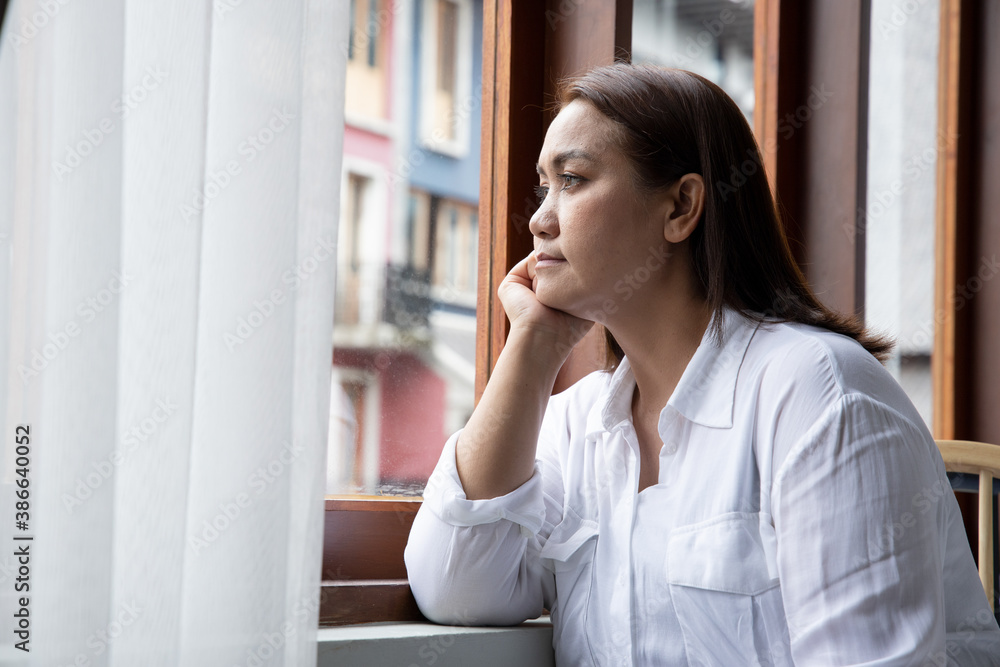 middle aged woman looking through window middle aged woman looking through window