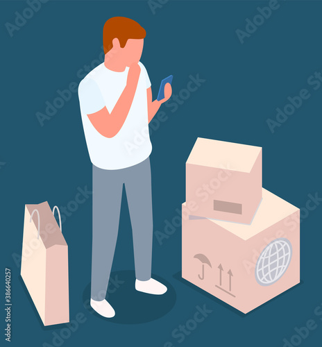 Online shopping mail delivery concept. A man with a smartphone in his hand stands near the cardboard boxes and package. The buyer receives the goods ordered on the Internet. Customer with purchases