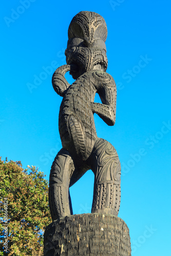 Traditional Maori wood carving of a human form in a park in Tauranga, New Zealand photo