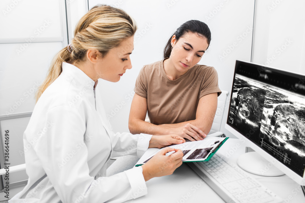 Endocrinologist consulting the woman, doctor analyzes the ultrasound of the patient's thyroid gland. Treatment of thyrotoxicosis, and hypothyroidism Endocrinologist consulting the woman, doctor analyzes the ultrasound of the patient's thyroid gland. Treatment of thyrotoxicosis, and hypothyroidism