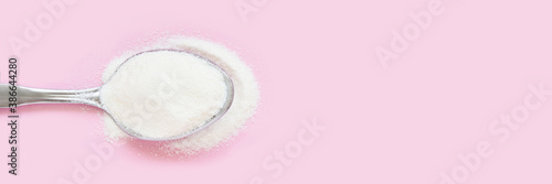 Collagen white powder. Pastel color background. Health product. Woman cosmetics concept. Sport supplement. Skincare cosmetics. Horizontal banner. Pink monochrome. Spoon