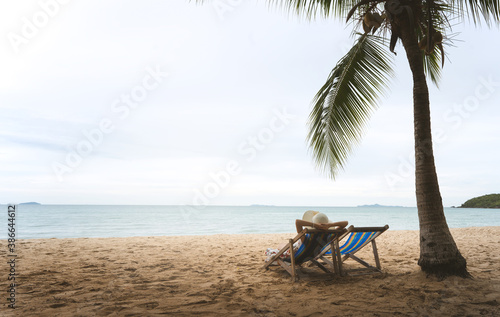 Rear view of young adult tourist asian woman relax sitting on outdoor beach chair at sea