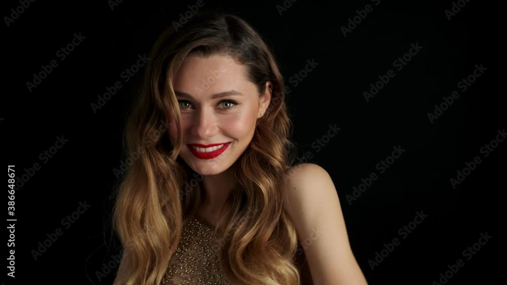 Young smiling beautiful woman with red lipstick posing isolated over black background and winking Young smiling beautiful woman with red lipstick posing isolated over black background and winking